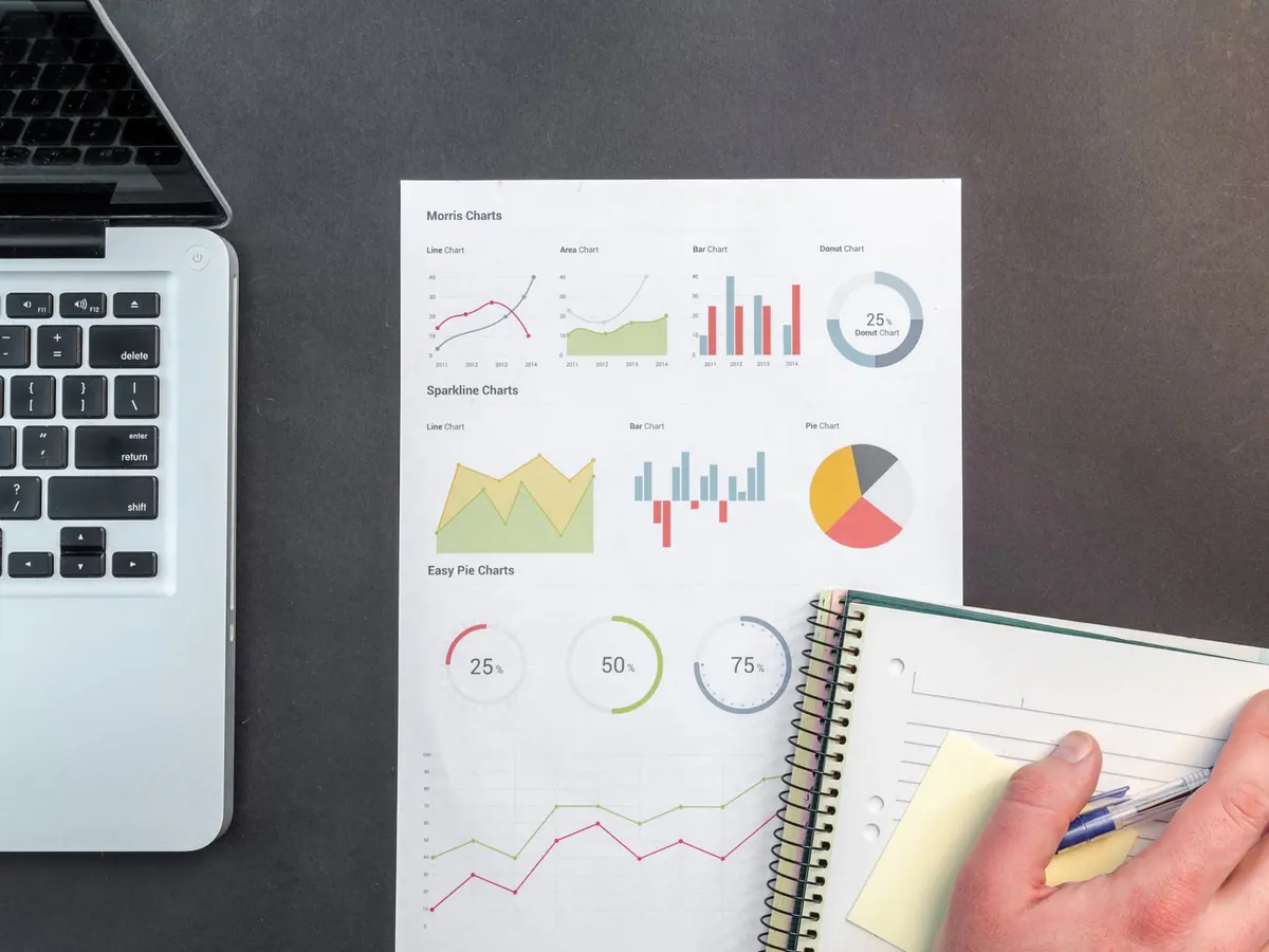 Printed charts beside a laptop and a notebook, an illustration for tracking payroll dates.